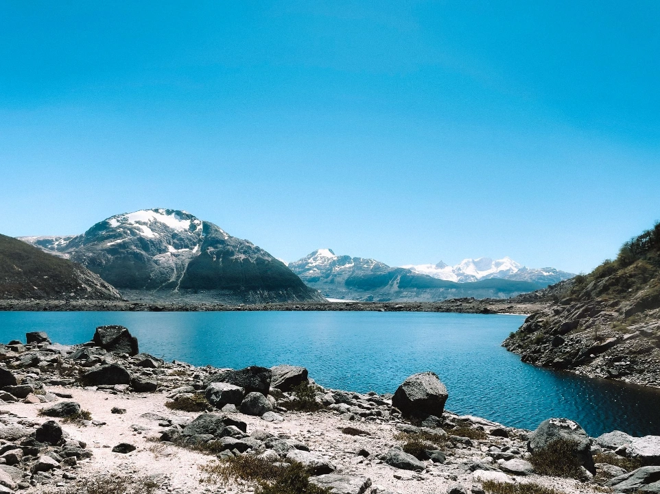 Mountain lake with snow covered peaks and a rocky shore