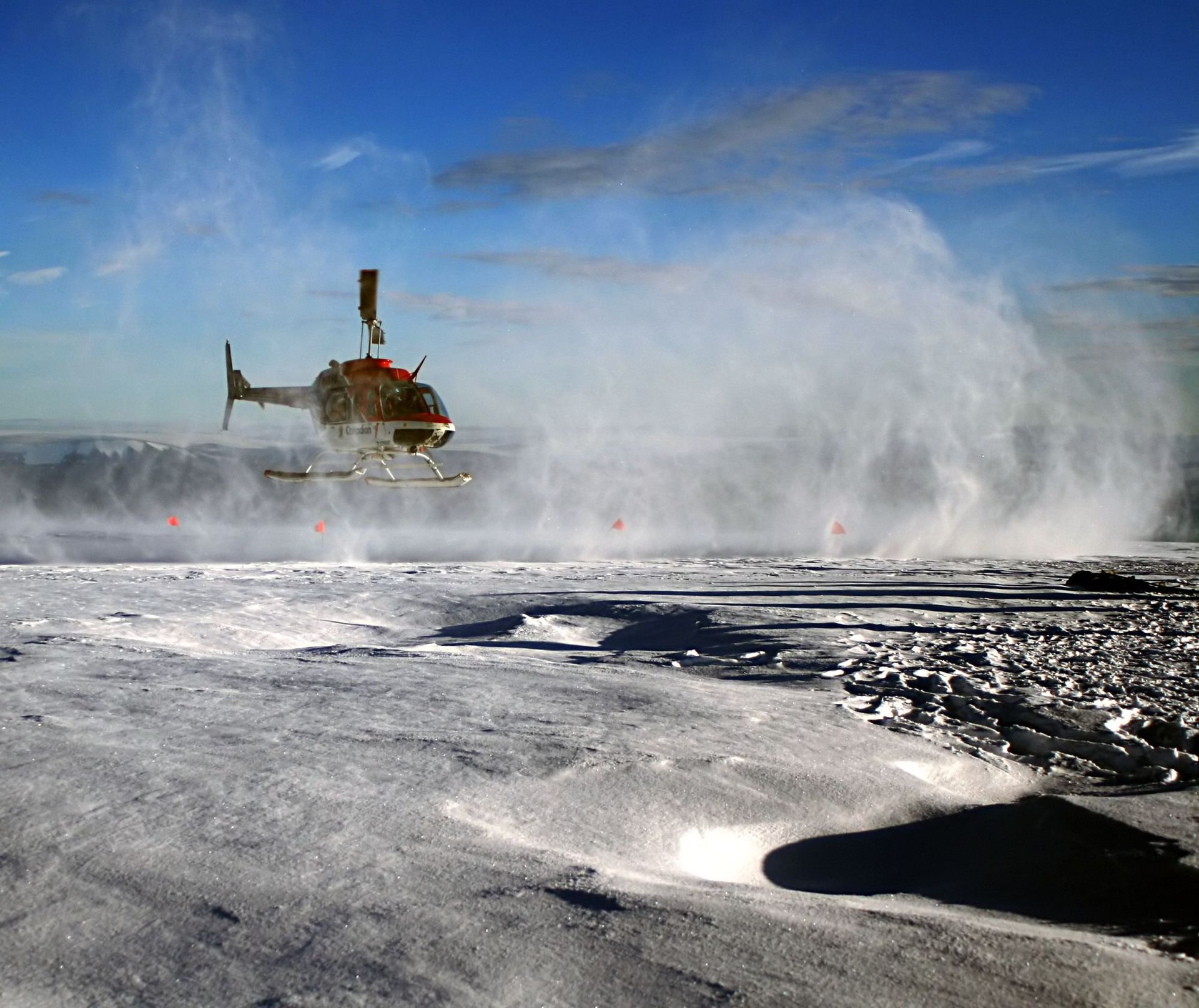 Helicopter with a veil of snow above the ice sheet in Greenland
