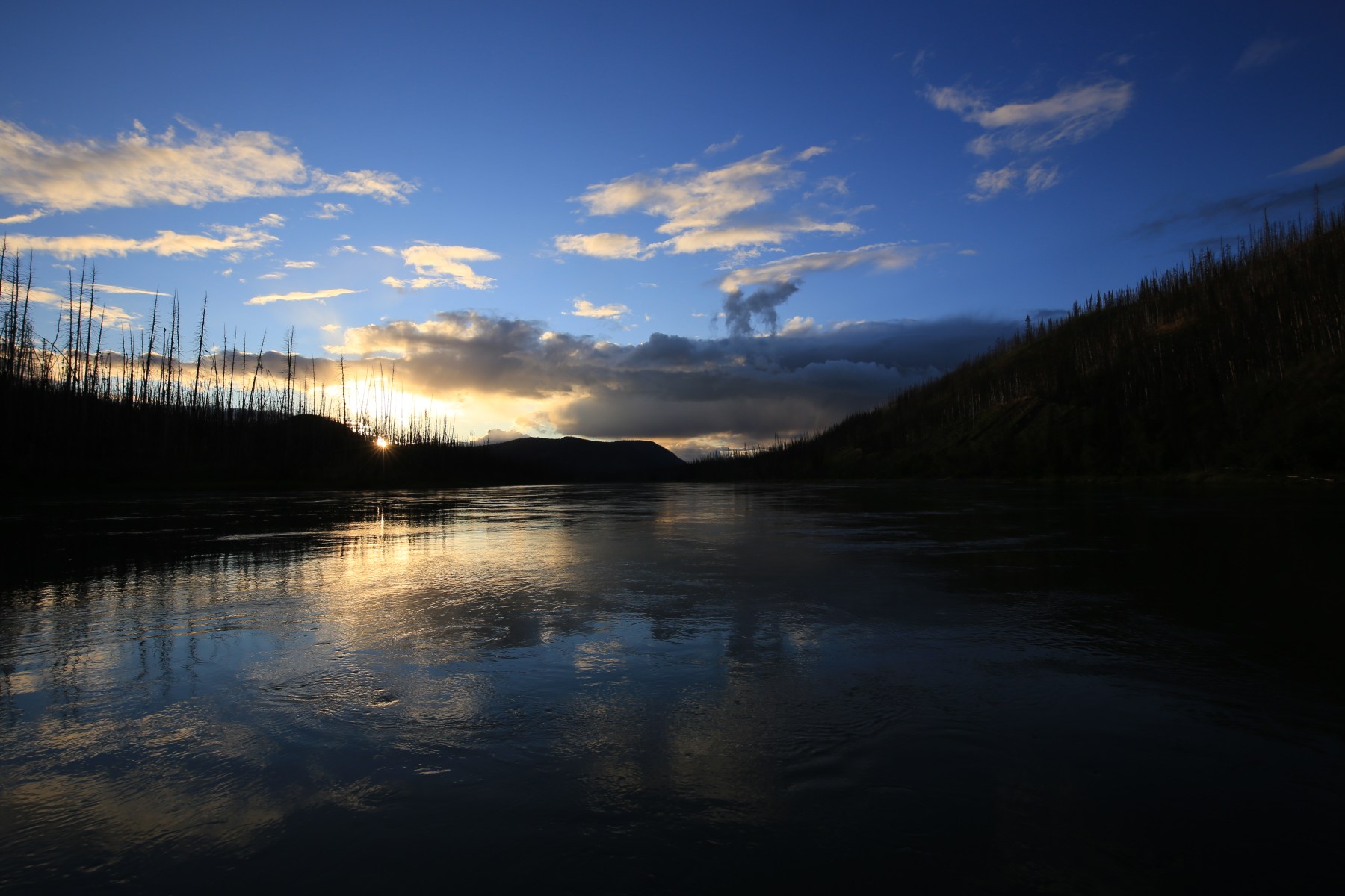 Zonsondergang boven de Yukon met silhouetten van verbrand woud