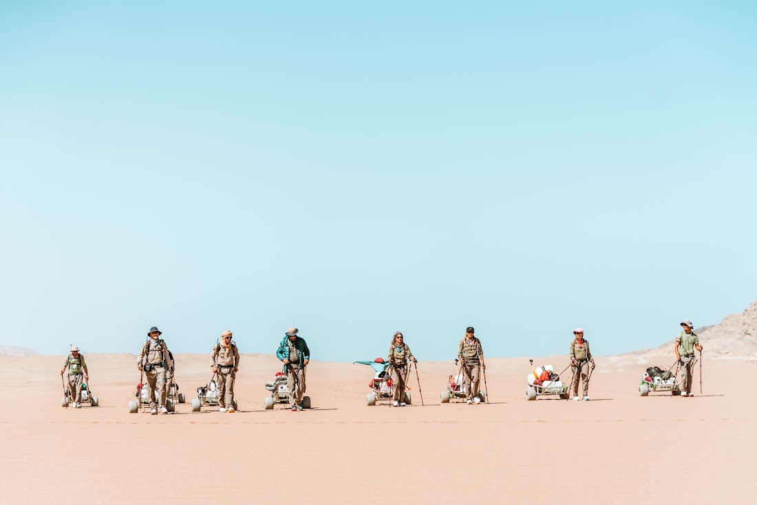 Team op een rij met bagagekarren in de woestijn tijdens een Element X expeditie